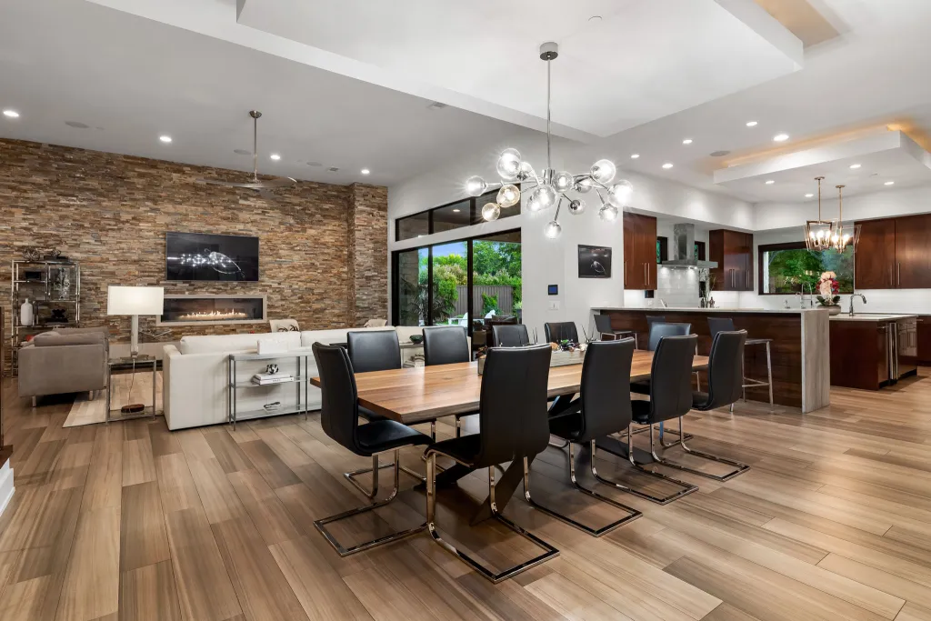 Open kitchen and dining room with a long table and a brick accent wall