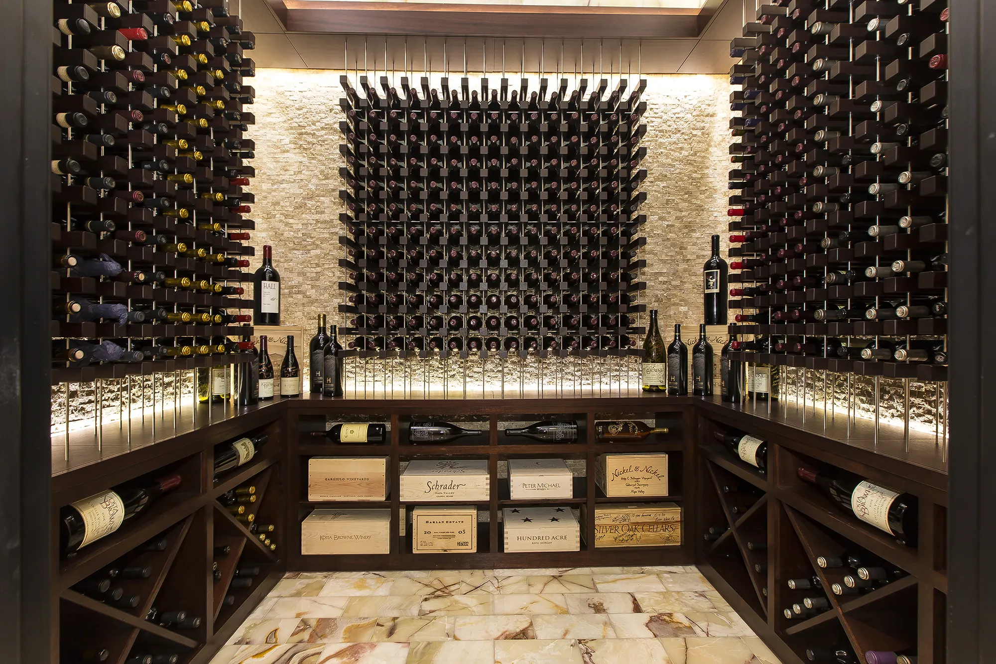 Wine room with floor-to-ceiling racks, a lit stone wall and display crates