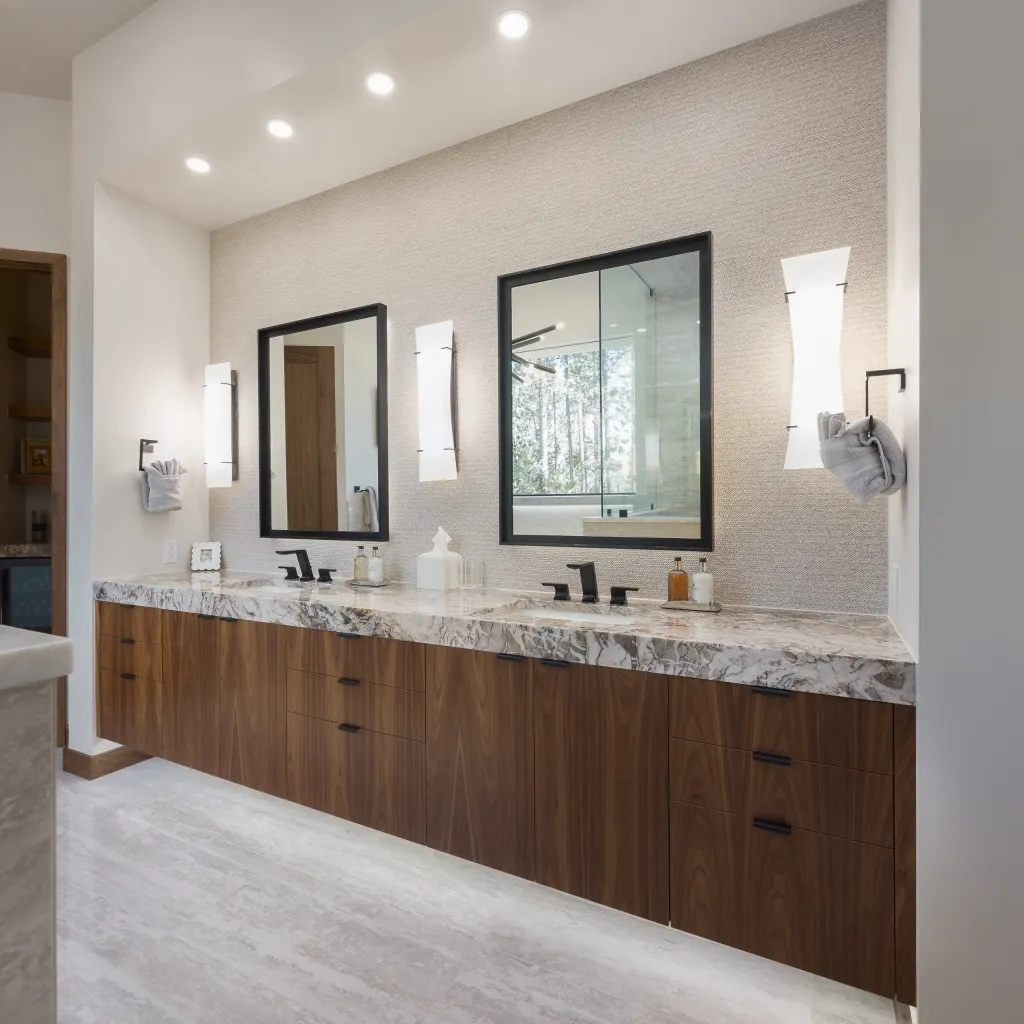 Double vanity with walnut cabinets and black-framed mirrors