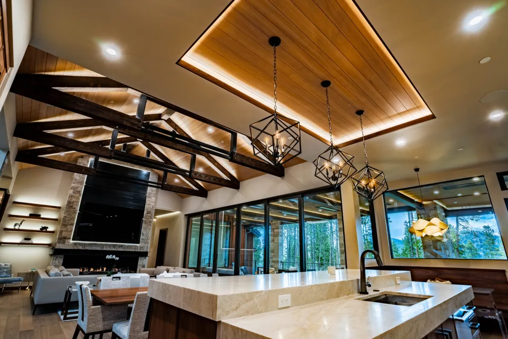 Kitchen island under geometric pendants and a lit wood ceiling