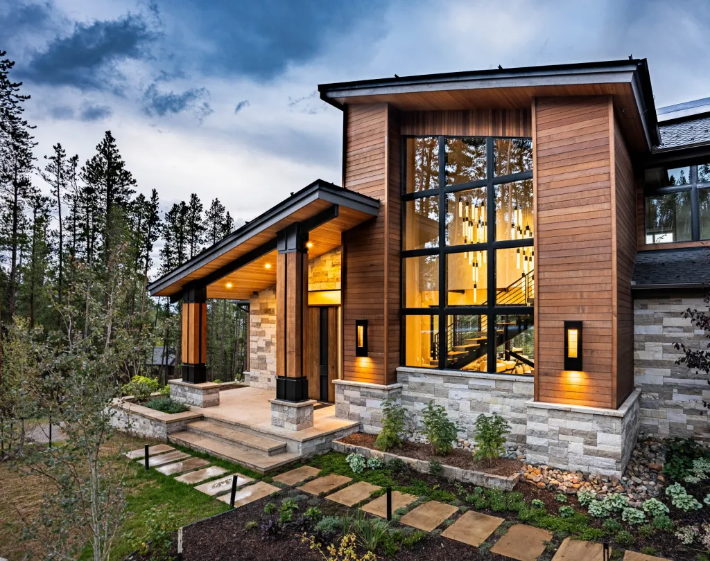Front exterior in timber and stone with tall windows and a stone path