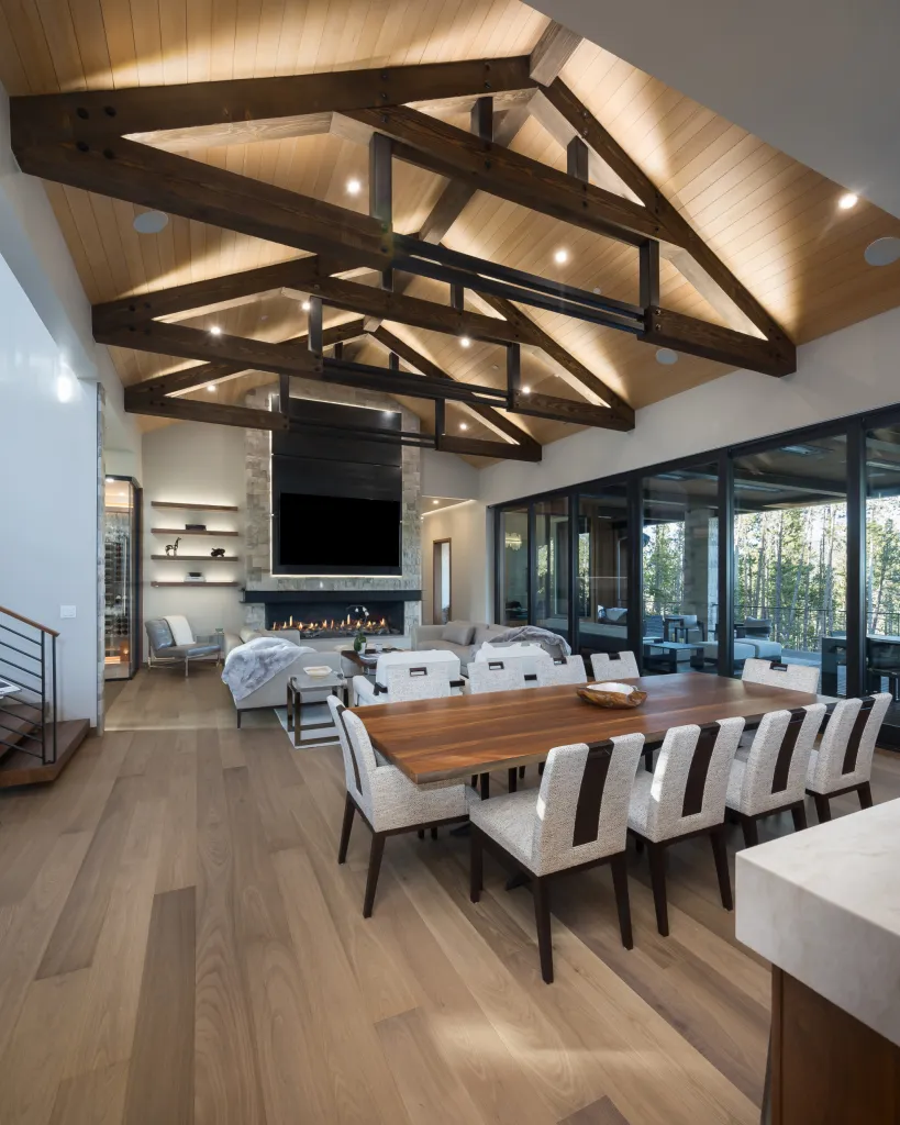 Great room with exposed timber trusses and a long dining table