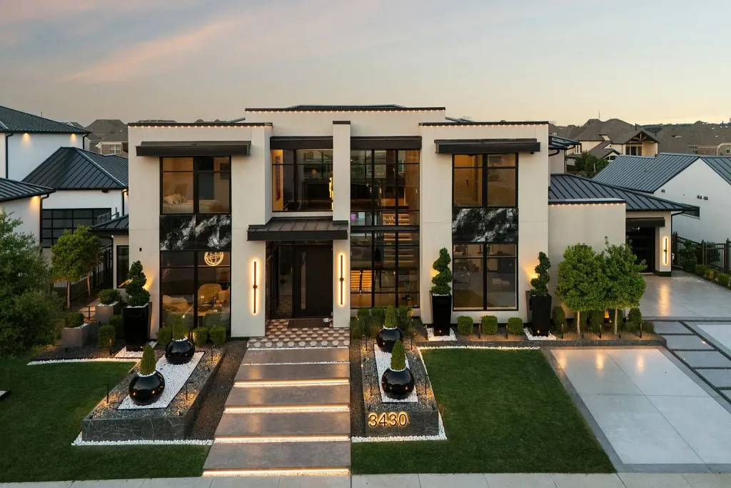 Front of a white contemporary home at dusk with a lit stone walkway