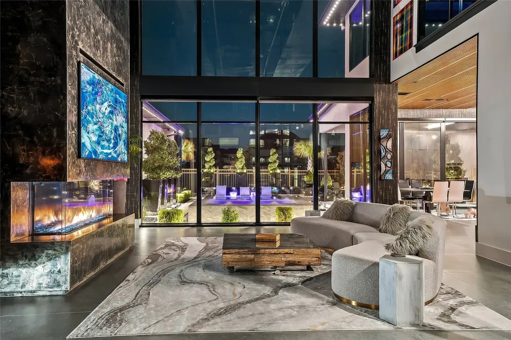 Living area with a marble-clad fireplace and a curved white sofa facing the pool