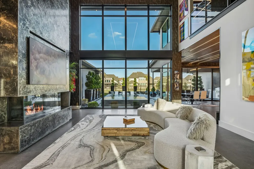 Living room with a marble fireplace wall and floor-to-ceiling windows to the pool