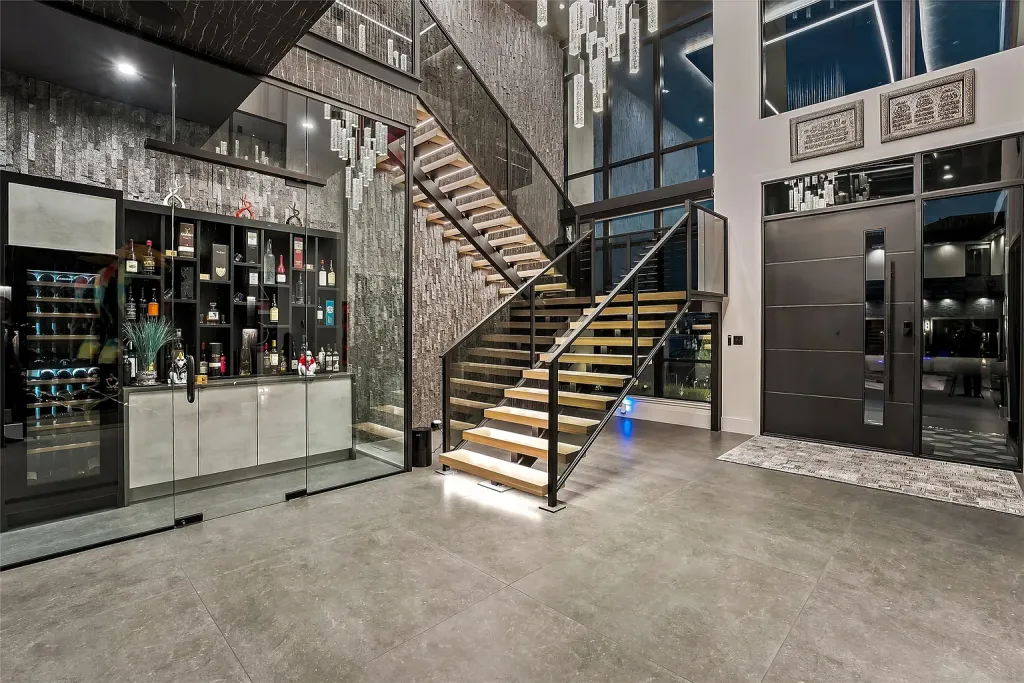 Floating staircase beside a glass-walled wine room and wet bar