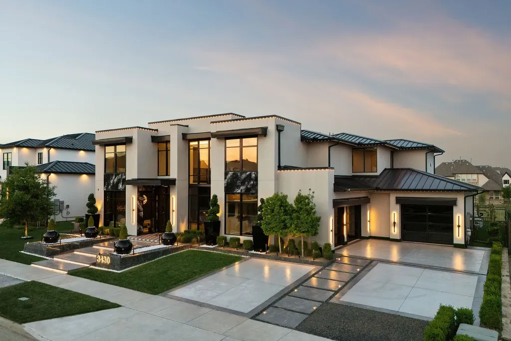 Angled view of a white contemporary home with dark metal roofs at dusk