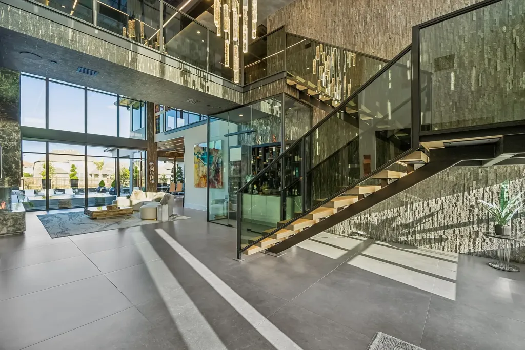 Floating staircase with glass railings in a two-story hall