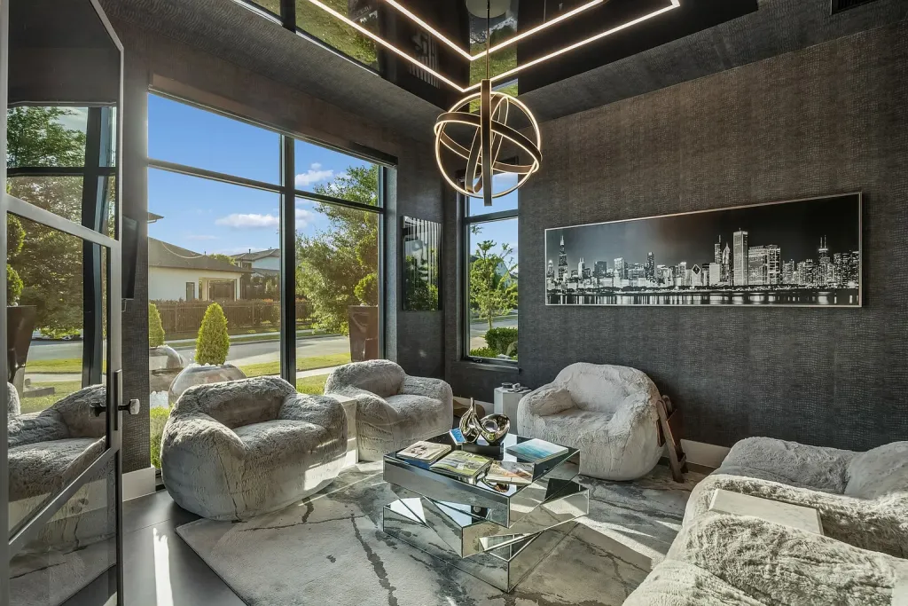 Lounge with sculptural chairs beneath a ring chandelier and a skyline print