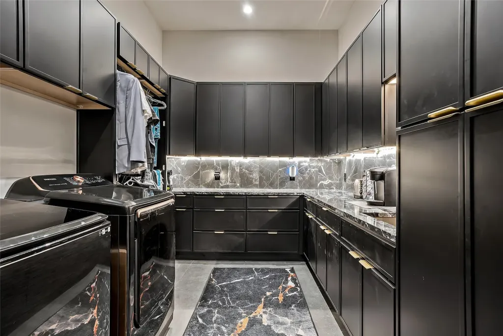 Laundry room with black cabinetry and marble counters