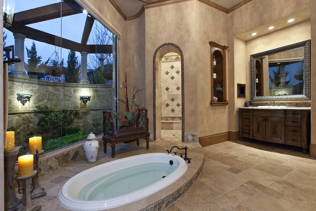Primary bath with a sunken tub, candlelit niches and a tall window