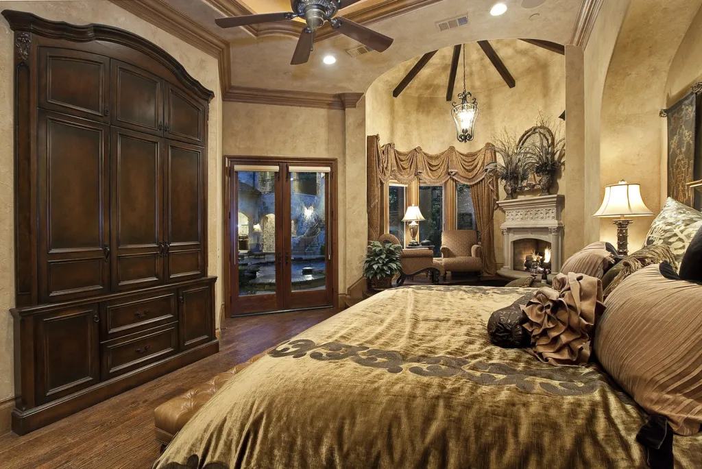 Primary bedroom with a carved armoire, vaulted beamed ceiling and fireplace