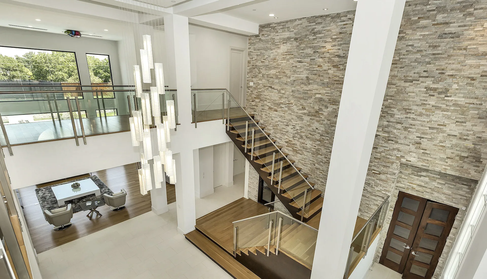 Double-height stair hall with a stone feature wall and glass railings
