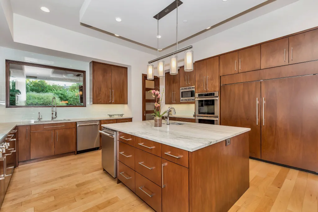 Kitchen with walnut cabinetry, a stone-topped island and pendant lights
