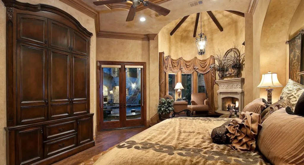 Primary bedroom with a carved armoire, beamed ceiling and fireplace