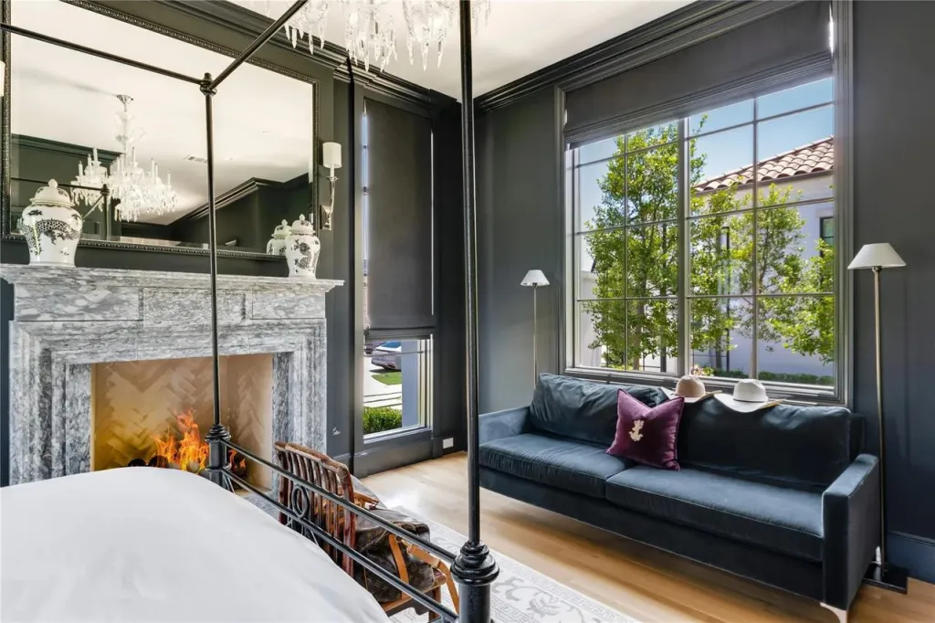 Primary bedroom with a stone fireplace, four-poster bed and sitting area