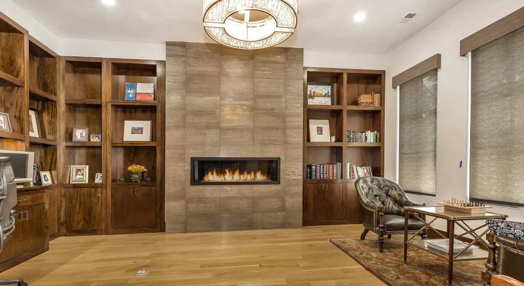 Study with built-in wood shelving around a tiled fireplace