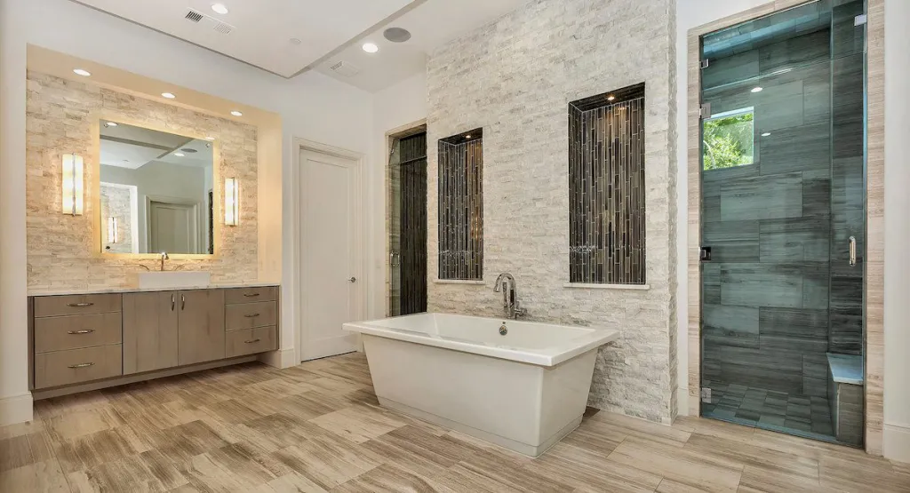 Primary bath with a freestanding tub, stone accent wall and glass shower