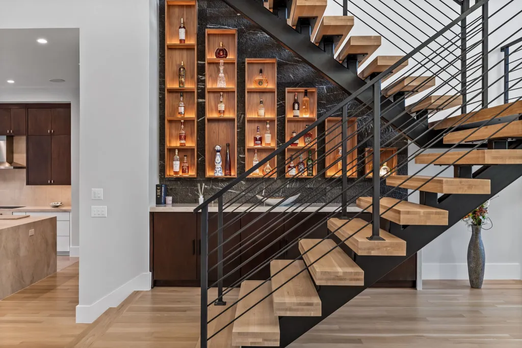 Floating timber staircase with a black steel railing and backlit display shelving