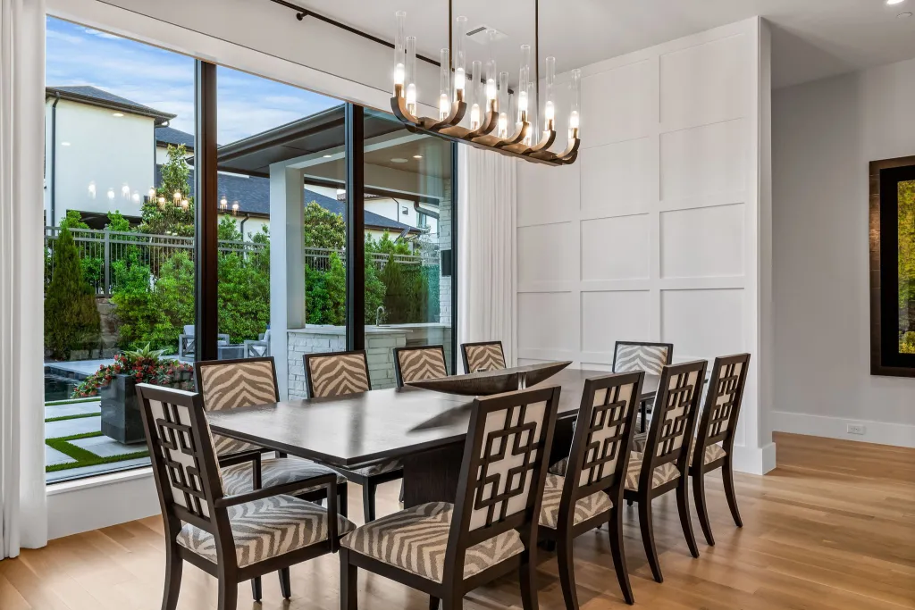 Dining room with a long table, upholstered chairs and a linear chandelier