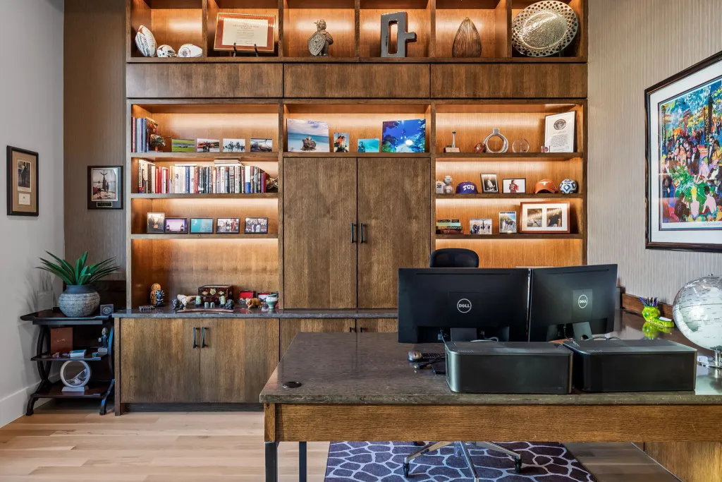 Home office with a wood desk and backlit built-in bookshelves