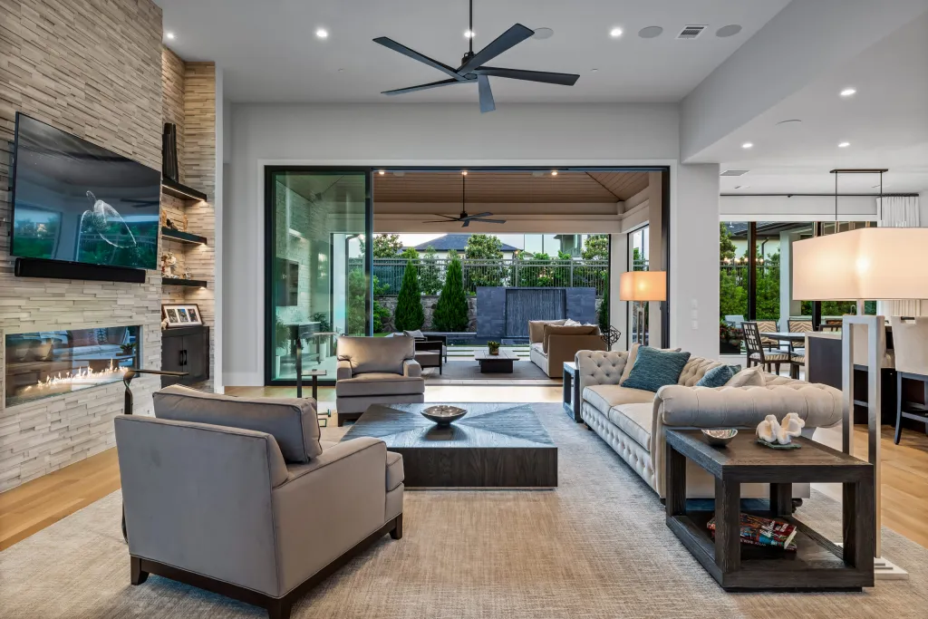 Family room with a stone fireplace wall opening to a covered patio