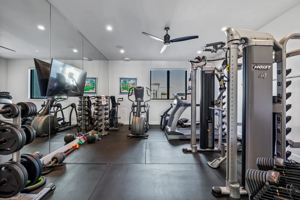 Home gym with strength equipment, a treadmill and a wall-mounted TV